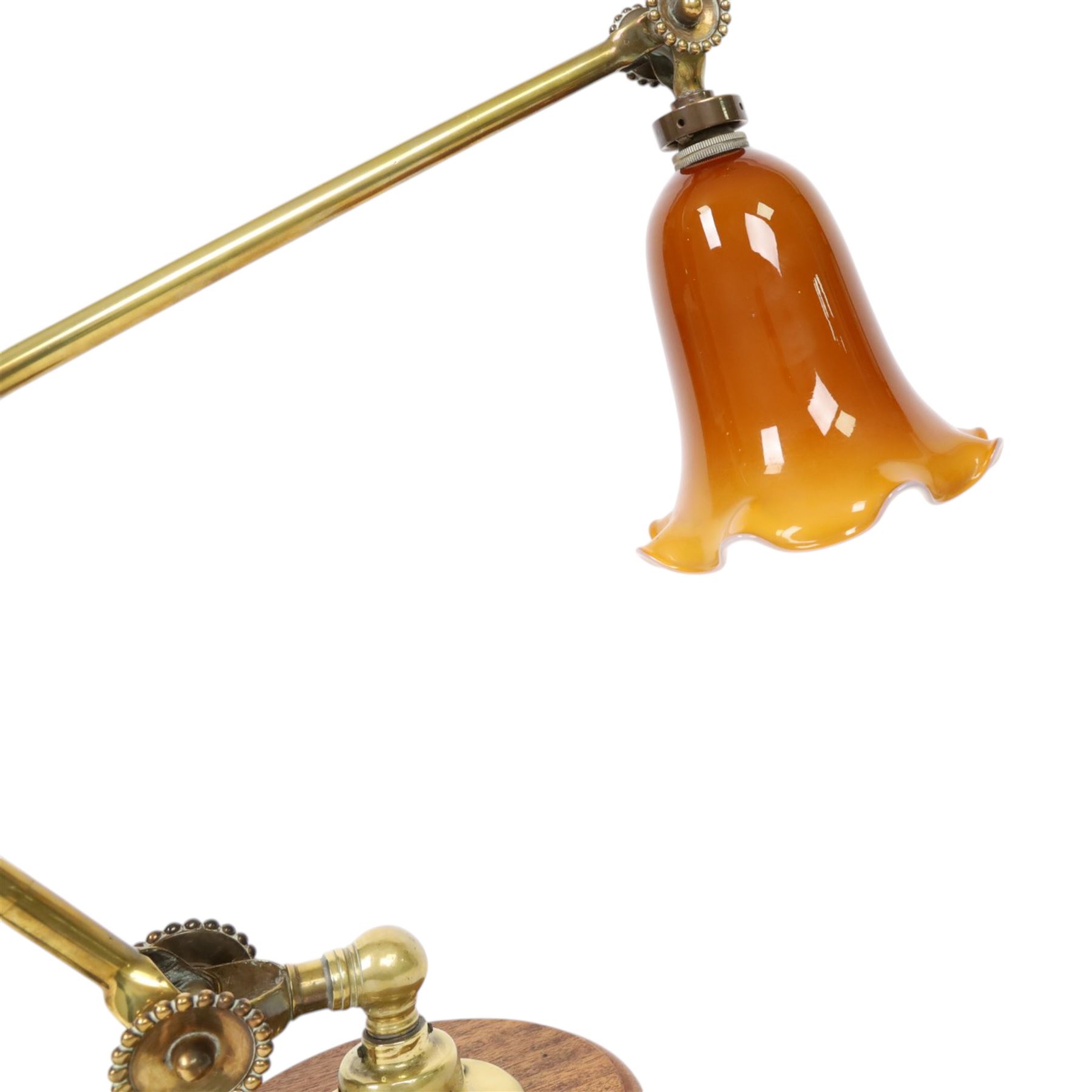 John Dugdill, early 20th century brass angle poise desk lamp, circa 1930's, with daisyhead joints and amber coloured lampshade, upon a circular wooden base 