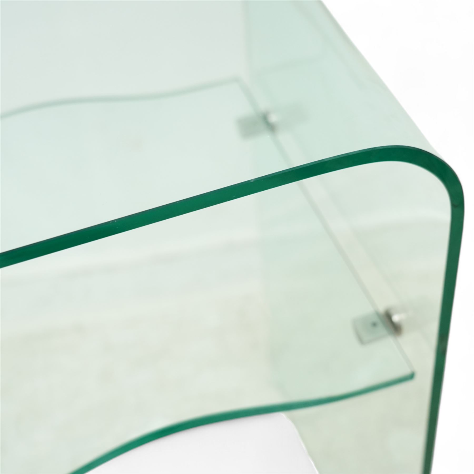 Contemporary glass two-tier console table of minimalist design, rectangular top with a single sheet of curved glass with a waved under tier supported with metal fittings 