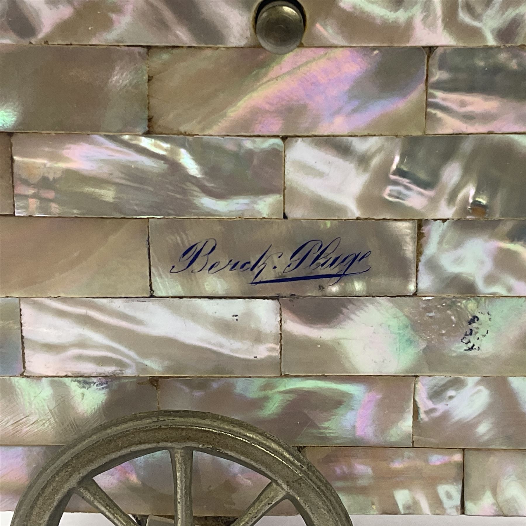 19th century French souvenir jewellery casket in the form of a bathing machine, having mother of pearl panelled tiled effect body, hinged roof/cover revealing a blue silk fitted interior with cushioned base, two silvered metal wheels, abalone shell door and mother of pearl steps, inscribed 'Berck Plage' in blue, H12cm, W13cm 