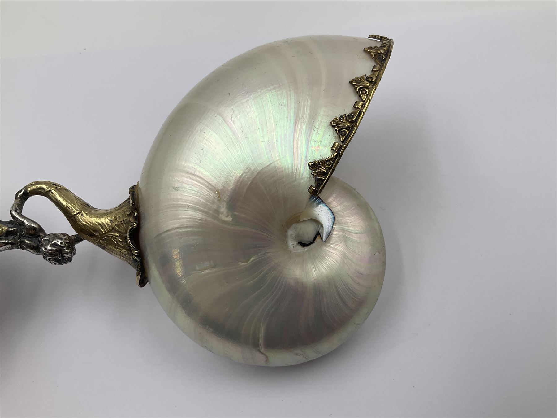 Modern limited edition silver mounted nautilus shell cup, no. 42/150, the pearlescent shell cup with silver-gilt strapwork to rim, upon a stem modelled as a putto supporting a gilt cornucopia and circular domed foot depicting Poseidon amongst swirling waves, hallmarked by St James House Company, London 1980,  H17.5cm