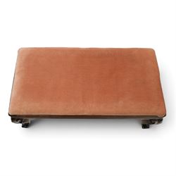 Victorian carved mahogany fender stool of generous proportions, the wide rectangular seat upholstered in rose fabric, shaped frieze rail over C-scroll and cartouche carved cabriole supports with scroll feet and brass castors