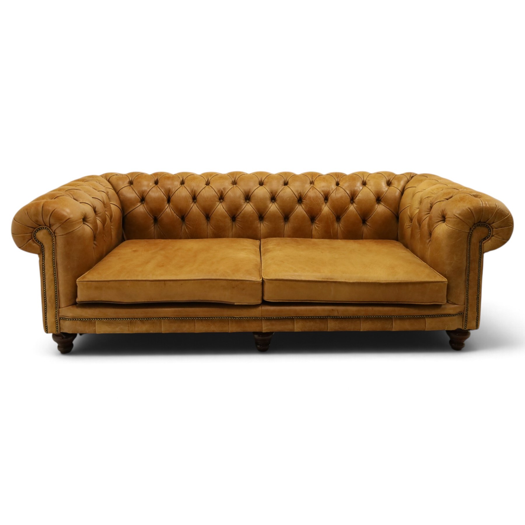 Distinctive Chesterfields - traditional shape four seater Chesterfield sofa, the rolled back and arms upholstered in deep-buttoned tan leather with matching loose seat cushions, raised on six turned supprorts