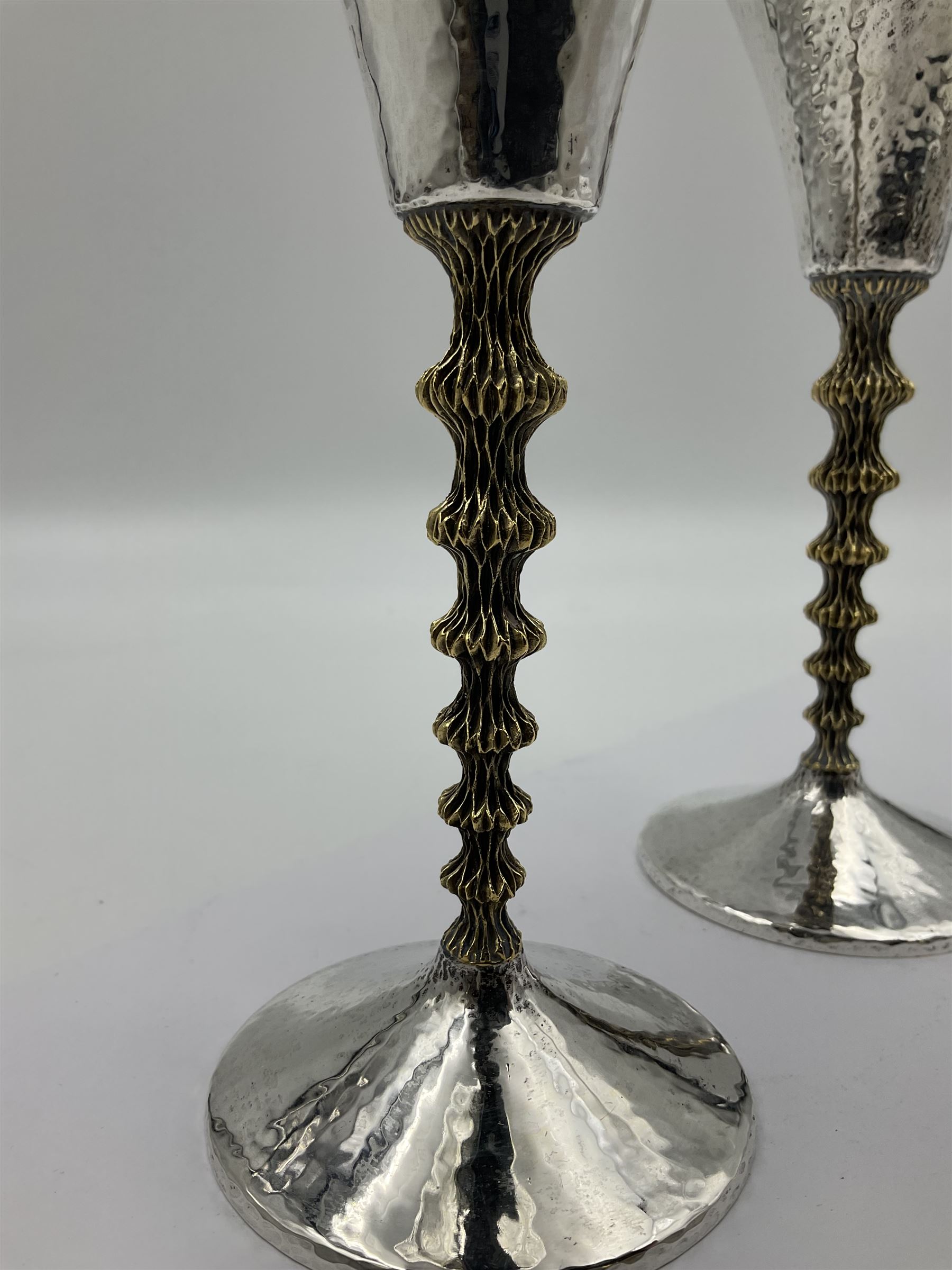 Pair of modern silver goblets by Stuart Devlin, the tapering cylindrical bowls each with spot hammered decoration and gilt interiors, the parcel gilt stems with signature textured detailing and six graduating knops, upon conforming spreading circular foot, hallmarked Stuart Devlin, London 1976, H17.7cm