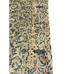 Persian Kashan pale green ground carpet, the field decorated with interlacing branch and stylised flower head motifs, shaped scrolling border panel