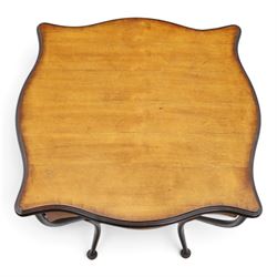 Art Nouveau style occasional table, serpentine shaped top with dark moulded edge, shaped apron and lower shelf, raised on four curved metal supports