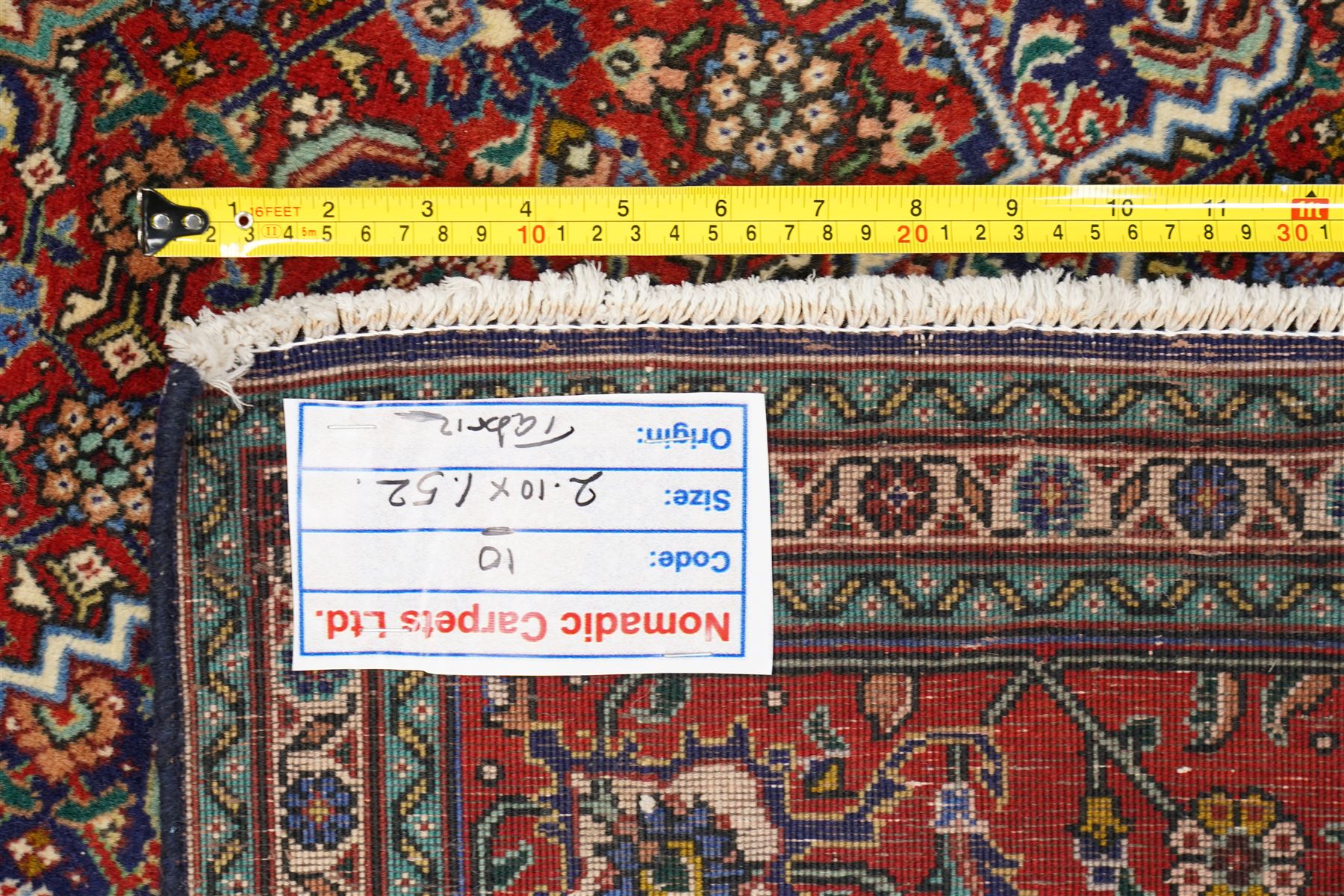 North West Persian Tabriz hand-knotted rug, ivory field with a central lozenge shaped medallion in indigo and madder red, issuing an ornamented arrangement of Herati style motifs, rosettes and angular floral elements, conforming spandrels on an ivory ground, main border in madder red with stylized vinery and palmettes, flanked by multiple guard border, with cotton fringe ends 