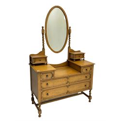 Early 20th century oak dressing chest, oval bevelled swing mirror back, drop centre and fitted with drawers, the drawer fronts decorated with mouldings, spiral turned supports
