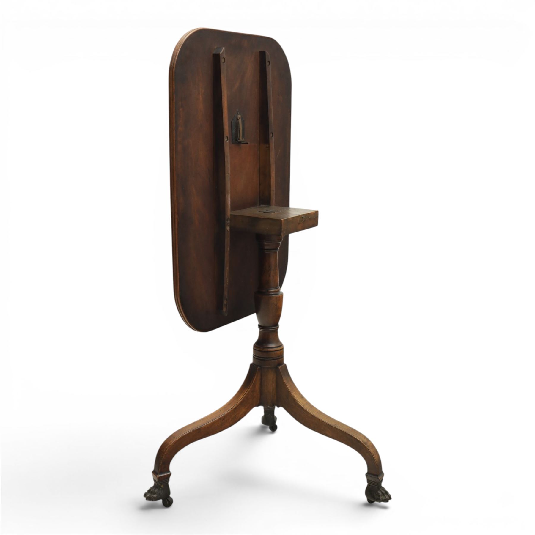 George III mahogany tripod table, rounded rectangular tilt top, raised on a turned column, on splayed supports, terminating brass claw feet above castors