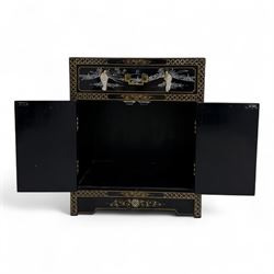 20th century Japanese Shibayama style black lacquered cabinet, rectangular form decorated with mother-of-pearl and hardstone figural inlay, the top with four standing figures, single frieze drawer above two cupboard doors, gilt painted borders and landscape