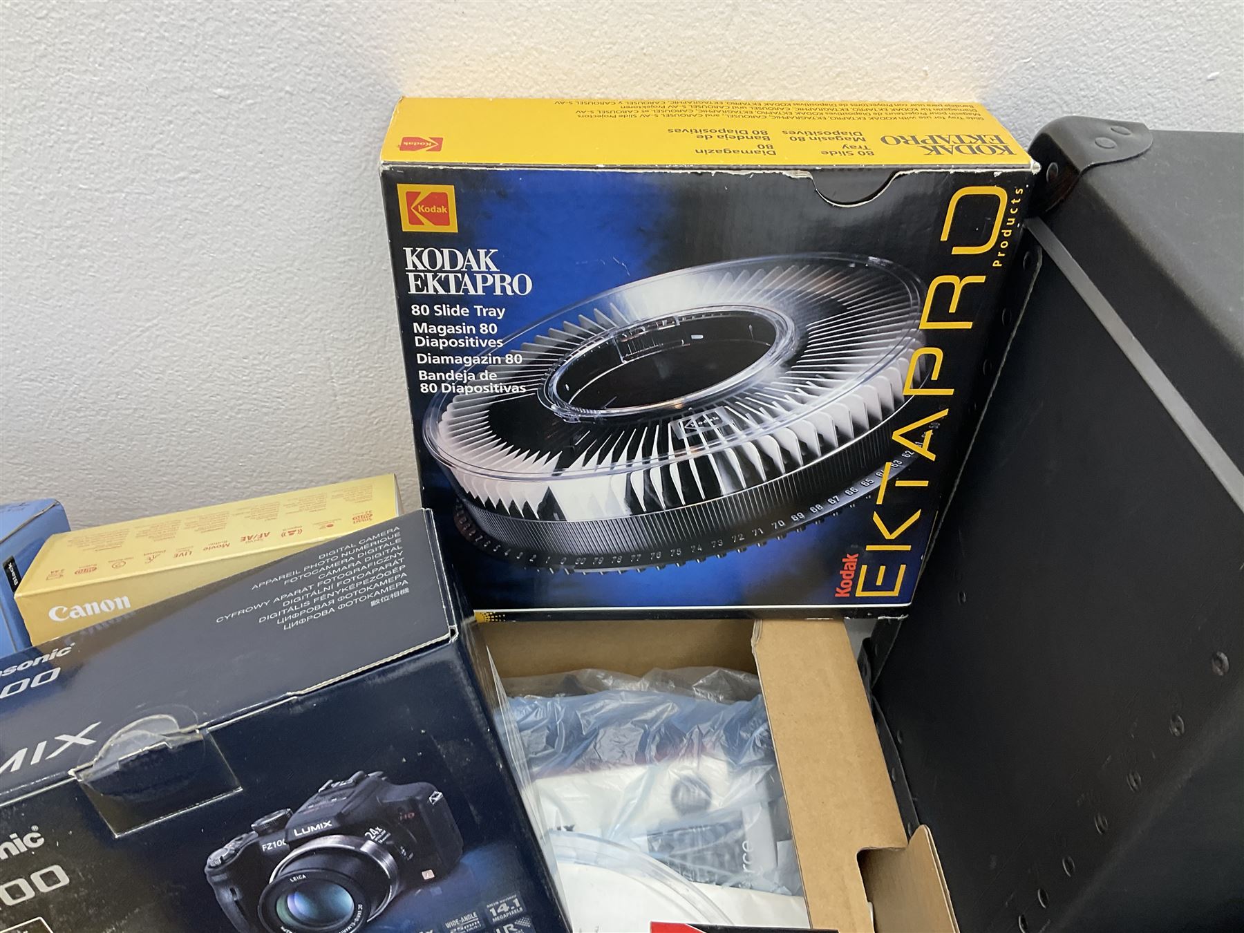 Large quantity of camera equipment in three boxes - Lumix GX1 camera, Canon EOS 500 camera, Lumix FZ100 camera, Pantax  MZ5n, various other cameras, Swift spotting Scope 20 x 60 in box,  Maxtor hard drive, three tripods, Kodak carousel projector, Pradolux slide projector, a selection of camera bags and other camera equipment. 