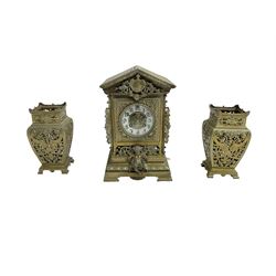 French- early 20th century 8-day  brass cased eight-day mantel clock and pair of pierced brass vases, clock case with an architectural pediment and pierced scrollwork on a recessed plinth raised on bracket feet, two part dial with a decorative centre and enamel chapter, Arabic numerals and spade hands, rack striking movement striking the hours and half hours on a coiled gong. With pendulum.