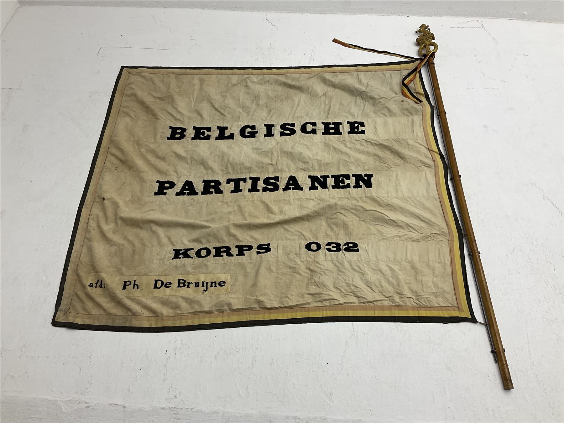 WW2 Belgian Partisan/Resistance two-sided banner embroidered in black on a cream ground 'Belgische Partisanen Korps 032 afd: Ph: De Bruyne' within a Belgian flag border; on wooden pole with gilded metal lion and laurel wreath finial