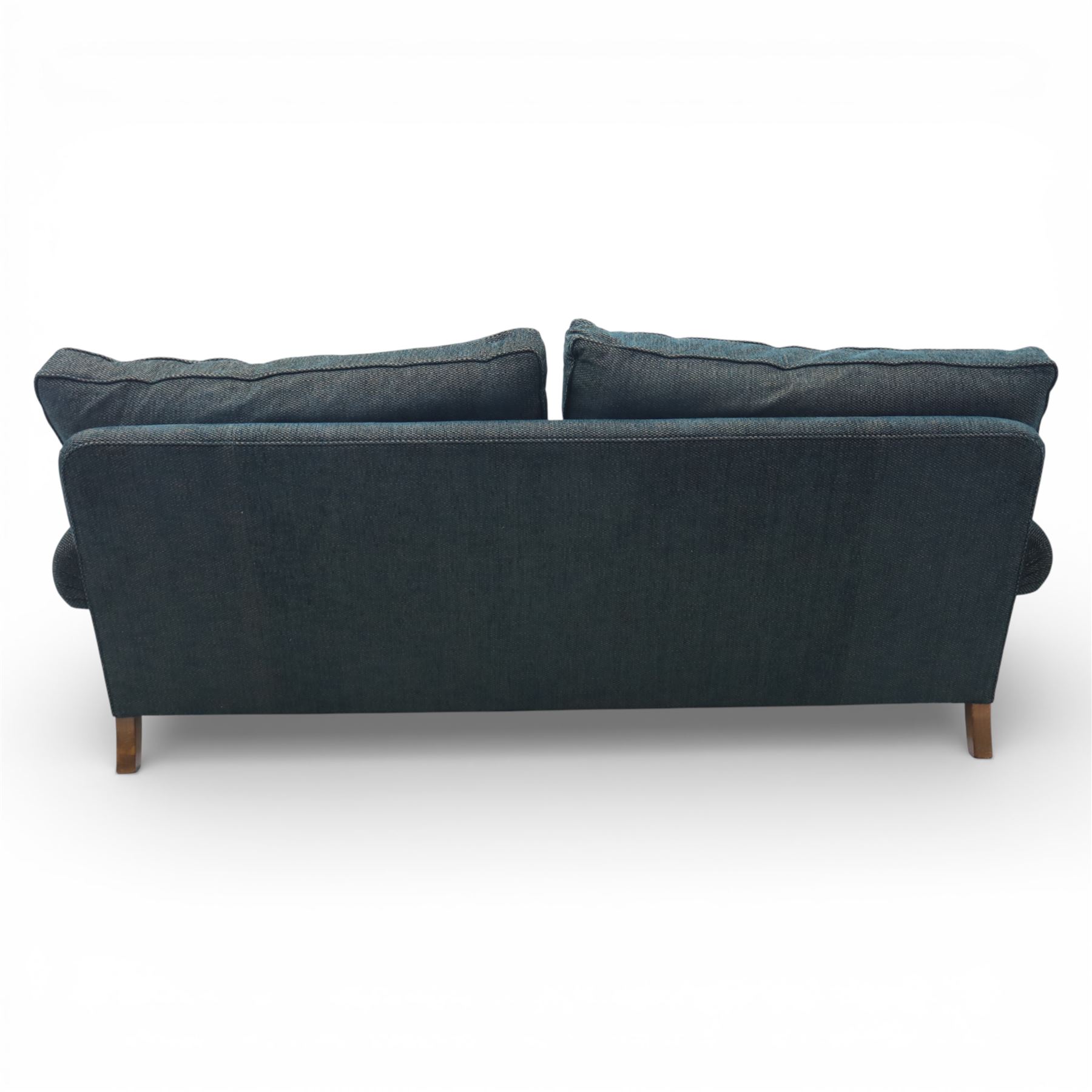 Late 20th century three seat sofa upholstered in green fabric, with gently rounded scroll arms, loose seat and back cushions, raised on turned wooden legs with castors, rear splayed legs
