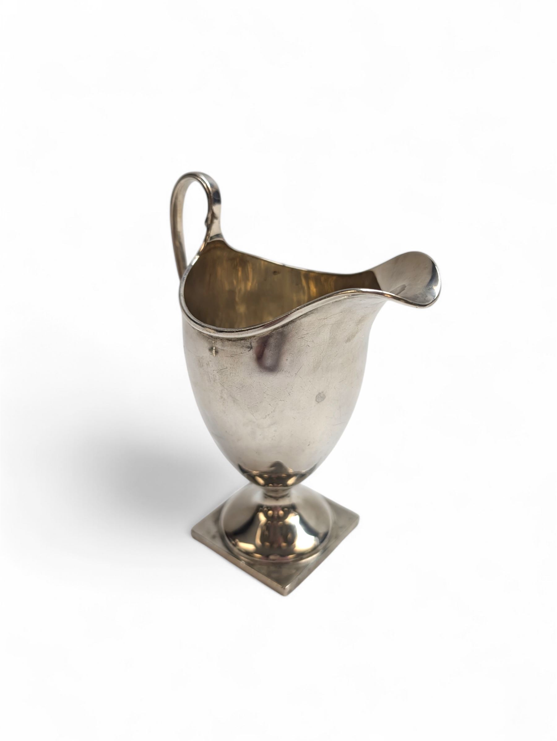 1920s silver cream jug, of helmet form with loop handle and upon a square base, hallmarked Charles Edwards, London 1926, including handle H15cm