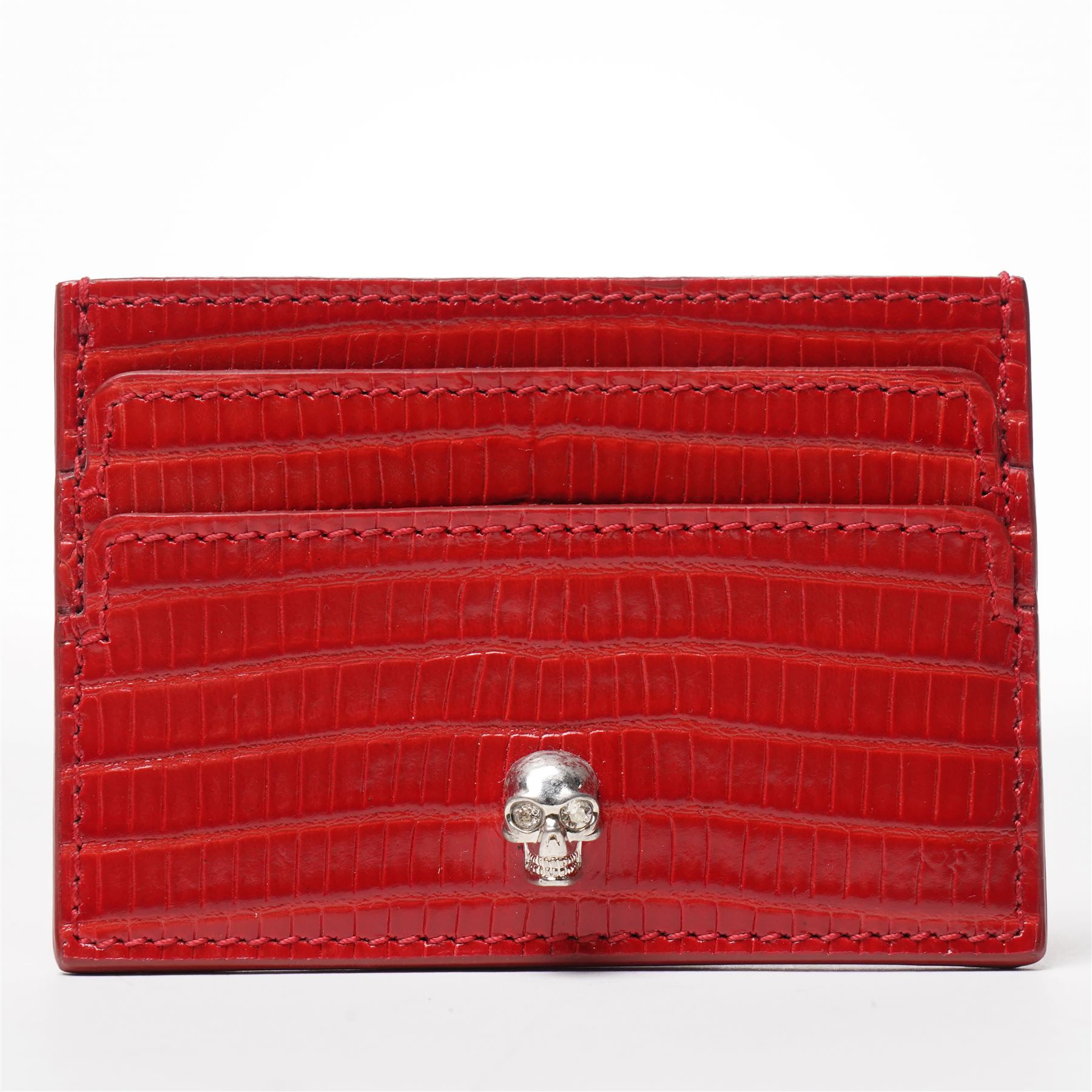 Alexander McQueen - a leather card holder in red lizard-effect leather, with multiple card slots and silver-tone skull motif to the front, unused, 7cm x 10cm