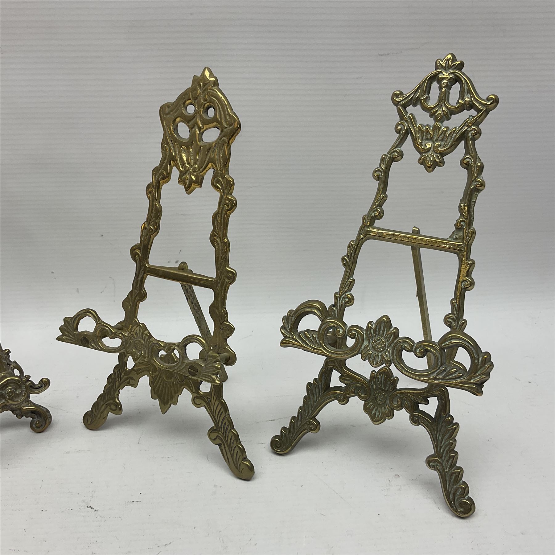 Nine ornate cast brass easel stands of various sizes, H24cm