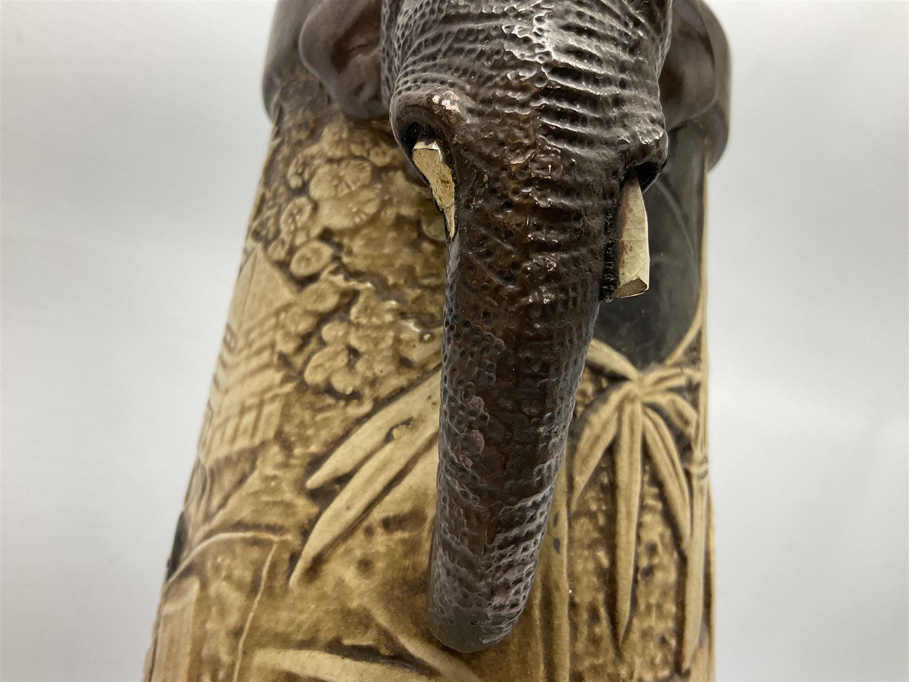 Pair of Bretby vases of tapering cylindrical form decorated with elephants, cranes and fishermen, the bodies with twin elephant mask handles, with coppered borders, raised upon three bun feet, stamped Bretby 2246 marks beneath, H32cm