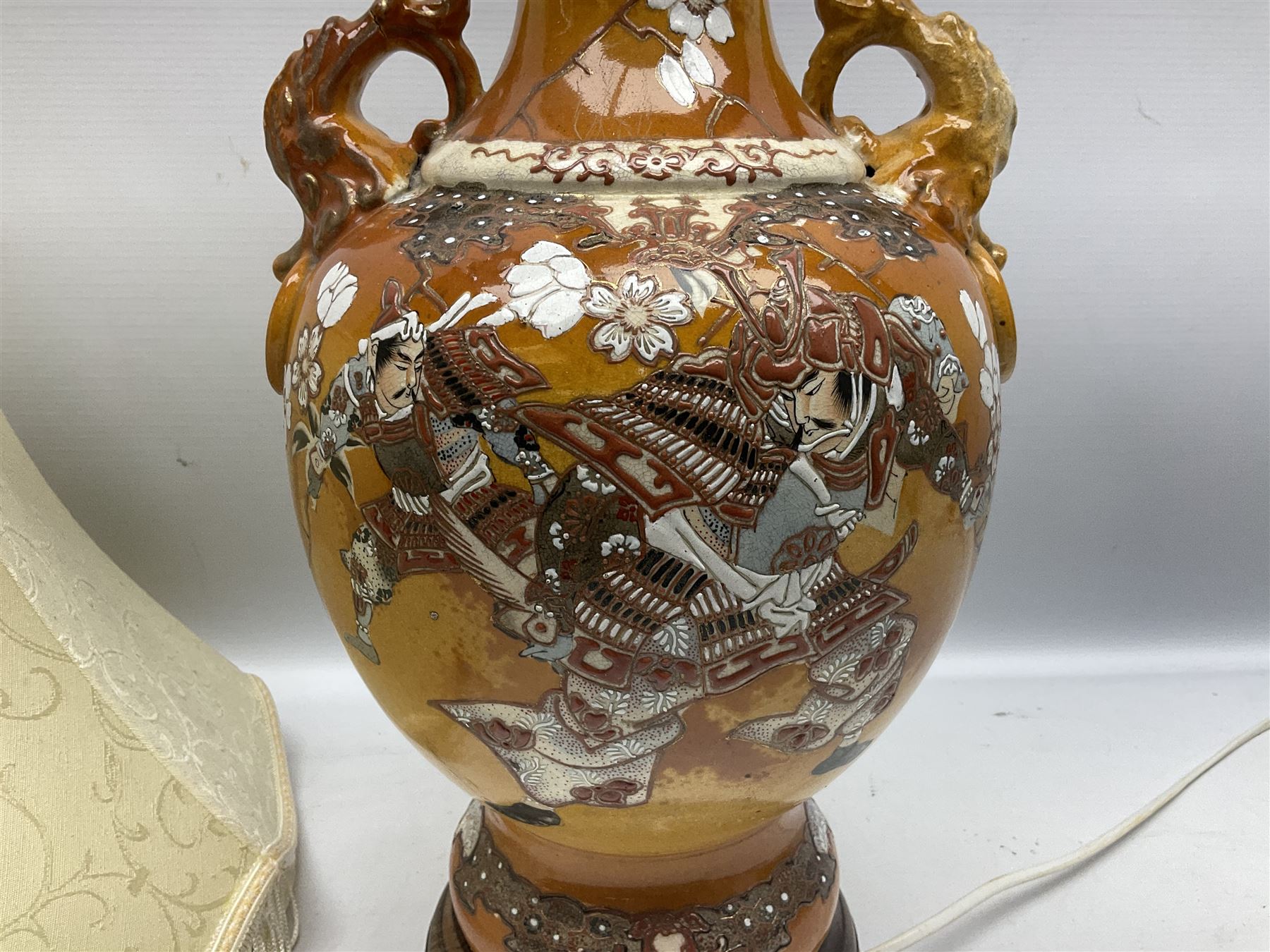 20th century Japanese vase converted to a lamp, the baluster form body decorated with samurai warriors and blossoming branches with twin handles, with wood base and fixtures, with tasselled fabric shade, H56cm excl shade