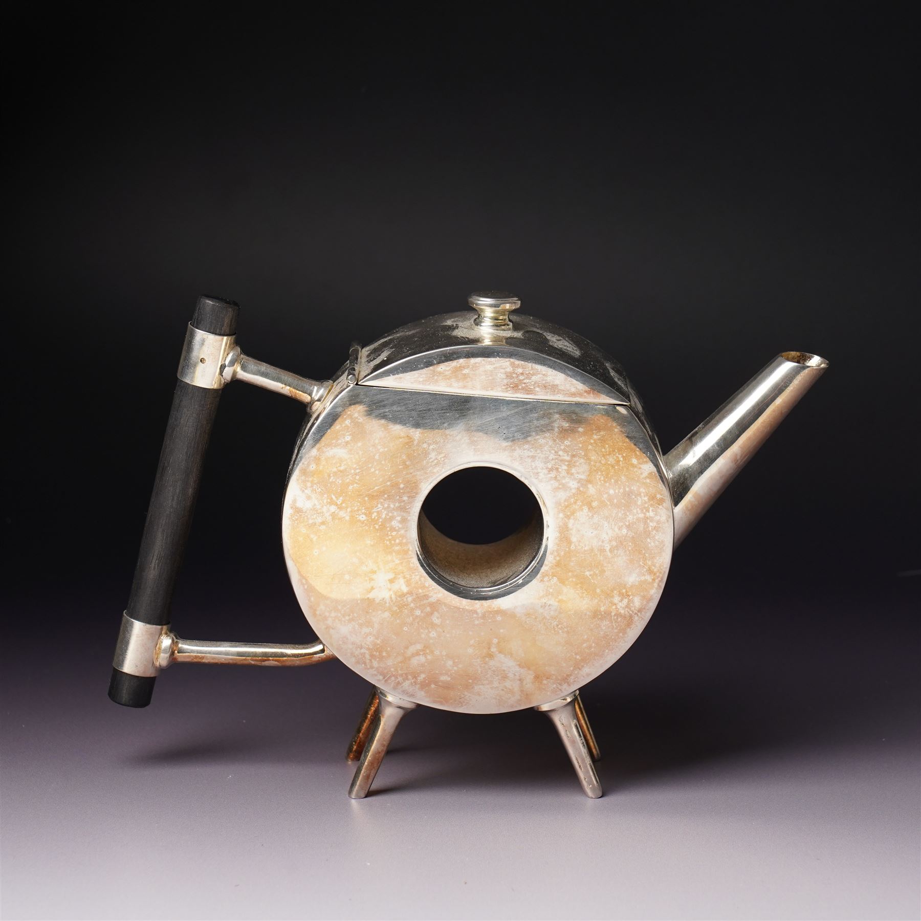 Manner of Christopher Dresser (1834-1904) - two art deco design silver plated teapots, of circular and square form with vacant centre, ebonised handles, each marked and with registration mark, max H18cm (2)