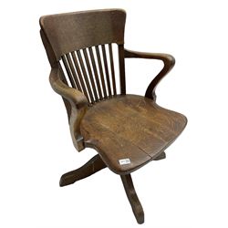 Early 20th century swivel office desk chair, shaped bar back over vertical rails, dished seat, on four splayed supports