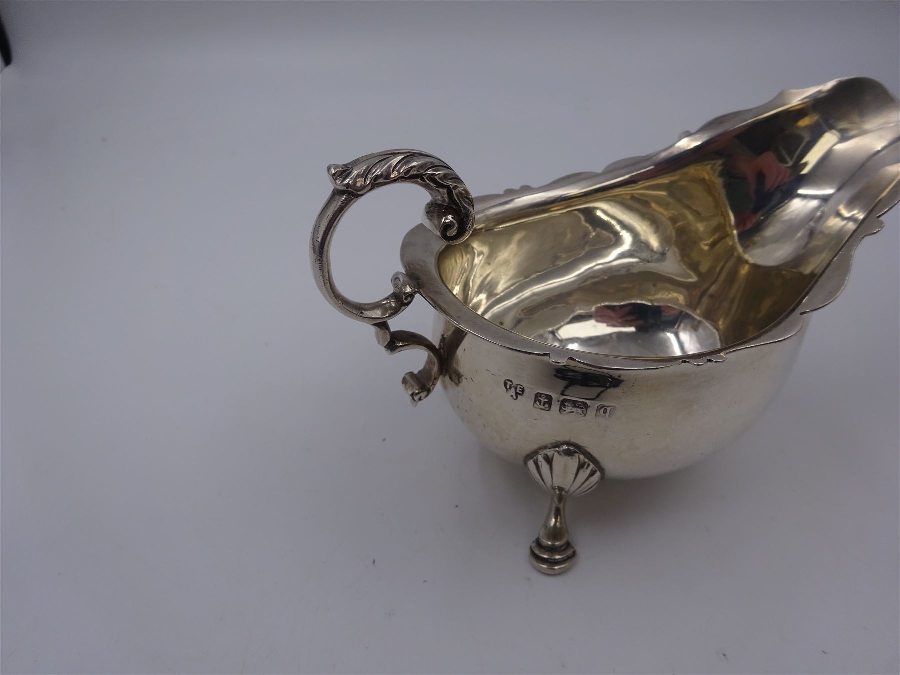 Early 20th century silver sauce boat, of typical form with shaped rim and acanthus capped flying C scroll handle, upon three palmette mounted hoof feet, hallmarked Thomas Edward Atkins, Birmingham 1915, including handle H8.5cm