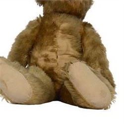Early 20th century teddy bear, probably German, blonde mohair bear with glass eyes, straw filled snout with stitched nose, hand stitched centre seam, wood wool filled body, jointed limbs, swivel head and hump to back, H67cm
