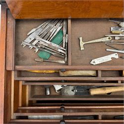 20th century black painted camphorwood lined tool chest, rectangular hinged lid over moulded edge, black painted exterior with iron straps and carry handles, the interior fitted with sliding lidded trays and drawers with turned handles, containing an assortment of hand tools