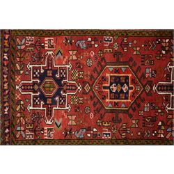 North West Persian Karajeh hand-knotted runner, madder red field with a series of shaped hexagonal medallions and cruciform motifs each enclosing geometric rosette devices linked by angular vine elements, field populated with stylized tribal ornaments, within narrow multiple borders decorated with repeating angular motifs framed by guard stripes of geometric devices, with cotton fringe ends  
