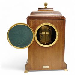 Edwardian- Early 20th century 8-day mahogany mantle clock, with a stepped pediment and brass finial, recessed brass pilasters and brass inlay to the front with a conforming plinth raised on bracket feet, silvered dial with Arabic numerals and steel spade hands within a glazed brass bezel, single train timepiece movement with pendulum and key.
