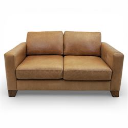 Modern two seat sofa in tanned leather, loose seat and base cushions, block arm rests above dark stained block supports 