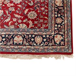 Persian crimson ground rug, interlacing floral stems linking ivory palmettes, rosettes and serrated leaves, within a navy floral border flanked by ivory patterned guards