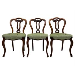 Set of six carved Victorian walnut balloon back dining chairs, button upholstered in green velvet fabric, back with foliate carved decoration supported on scroll form legs 