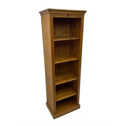 Narrow pine open bookcase, projecting moulded cornice over four open shelves, on plinth base