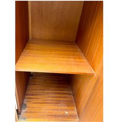 William Lawrence - mid-20th century teak double wardrobe, upper storage section over twin doors featuring recessed handles and contrasting horizontal panel, enclosing hanging rail compartment, towel rail, mirror, shelves and drawer, on plinth base with concealed castors