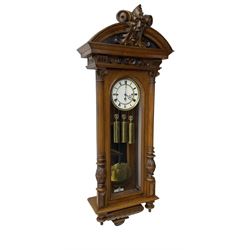 German- Late 19th century 8-day walnut cased Vienna regulator wall clock c1870,  with a broad arched pediment and heavily carved grotesque to the centre, carved frieze beneath with reeded columns to the front of the fully glazed door, carved ogee plinth and pendants to the base, two part enamel dial with Roman numerals and pierced steel hands, ebonised pendulum rod with a brass faced bob and beat plate, three matching brass cased weights and pulleys, grand sonnerie three train striking movement with a deadbeat escapement striking the quarters and hours on two coiled gongs. 
With repeat work.