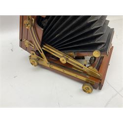Ensign 'The Sanderson' folding plate camera in mahogany and lacquered brass, field model with canvas wrapped box, two mahogany photographic plates, 'Busch rapid Symmetrical F:8' lens,  and a wooden tripod 