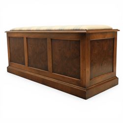 Traditional design figured elm blanket chest, with padded striped upholstered seat, over a hinged top with panelled sections below raised on a plinth base