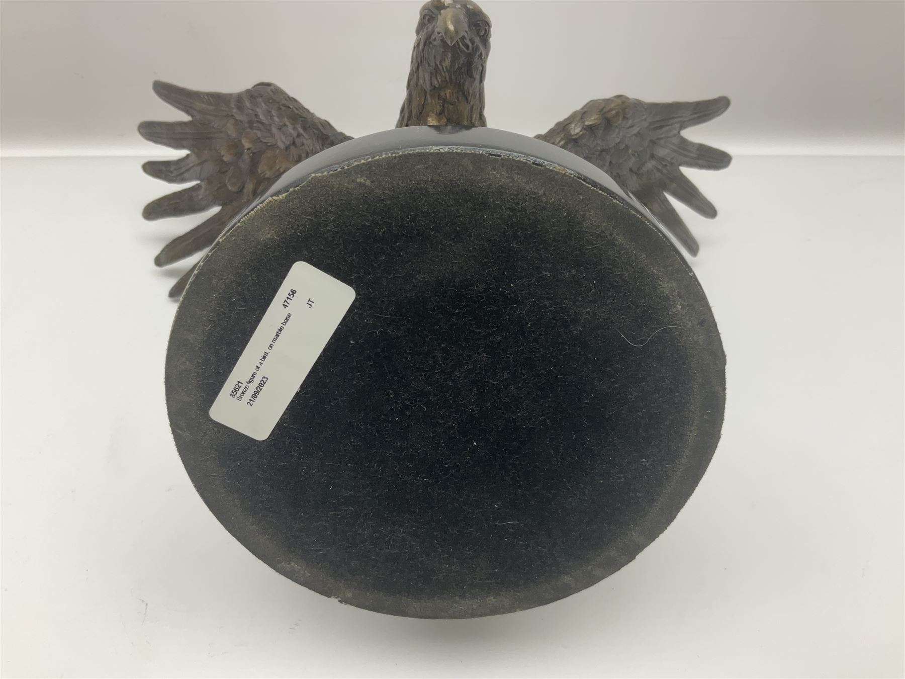 Bronze eagle, modelled in a standing position with wings spread, raised on a black veined marble circular plinth base, H29cm