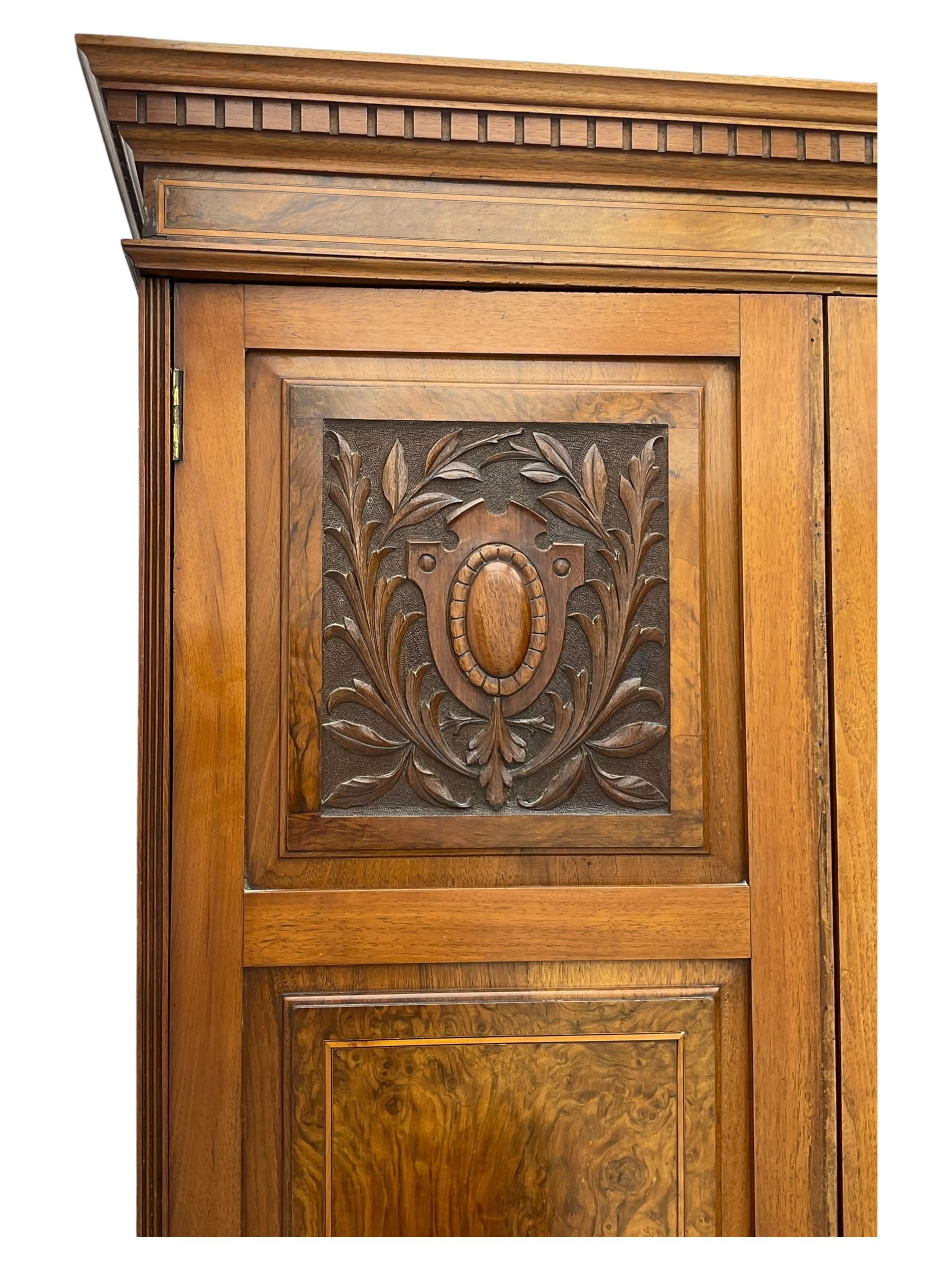 Late Victorian walnut triple combination wardrobe, projecting moulded and dentil cornice, central shaped bevelled mirror glazed door, cartouche and curled leaf carved panels over figured walnut veneered panels, fitted with drawer to base, on bracket feet