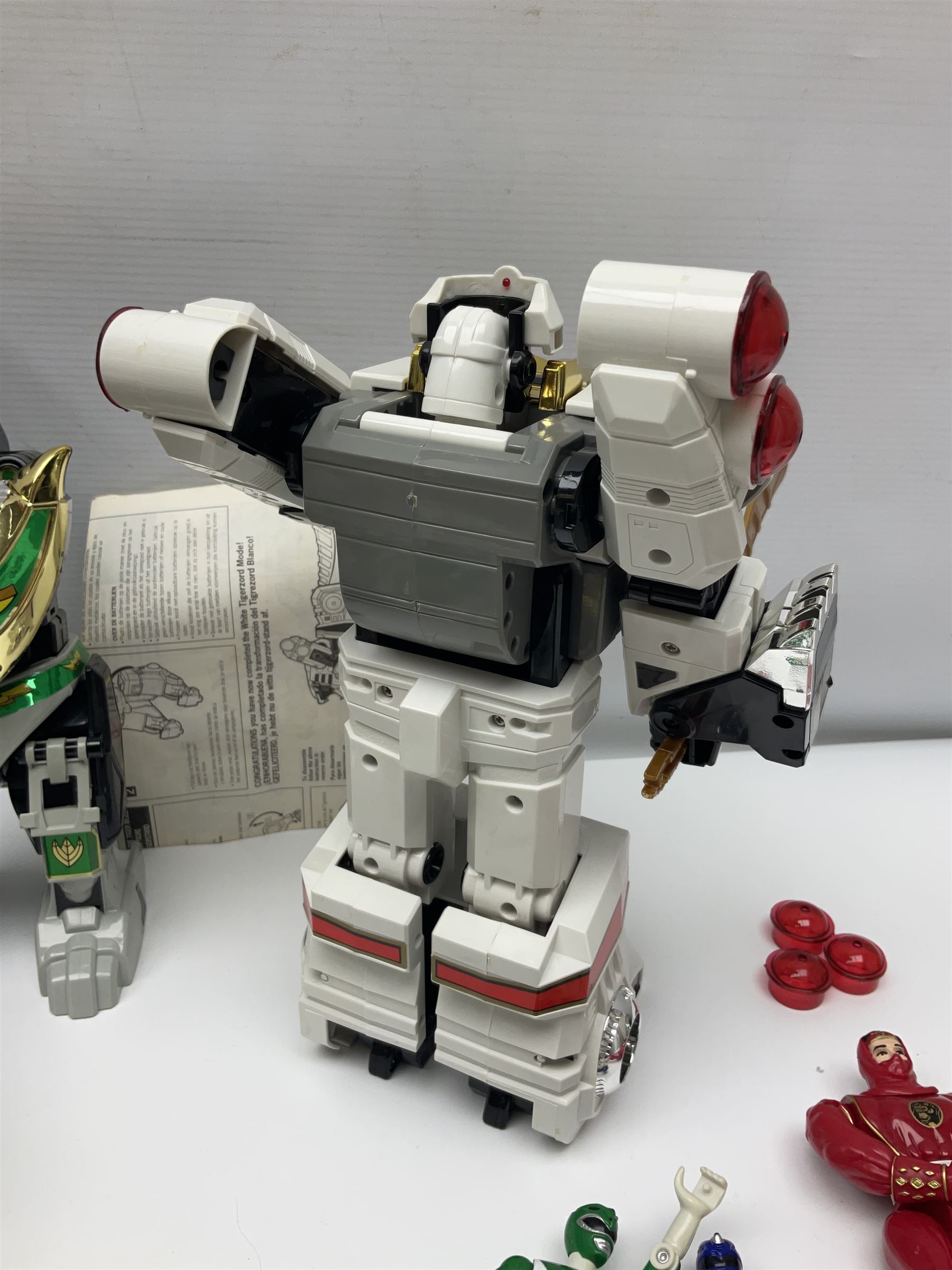 Collection of early 90s Mighty Morphin’ Power Rangers Zords, figures and accessories. Titanus the Carrier Zord, marked Bandai 1991; Green Dragonzord, incomplete; 1994 White Tigerzord with original instruction manual; 1993 Triceratops Dinozord, Mastodon Dinozord and Sabertooth Tiger Dinozord, Pterodactyl Dinozord, missing guns; with 1993 Power Morpher and original Power Coins, with further related figures, accessories and weapons