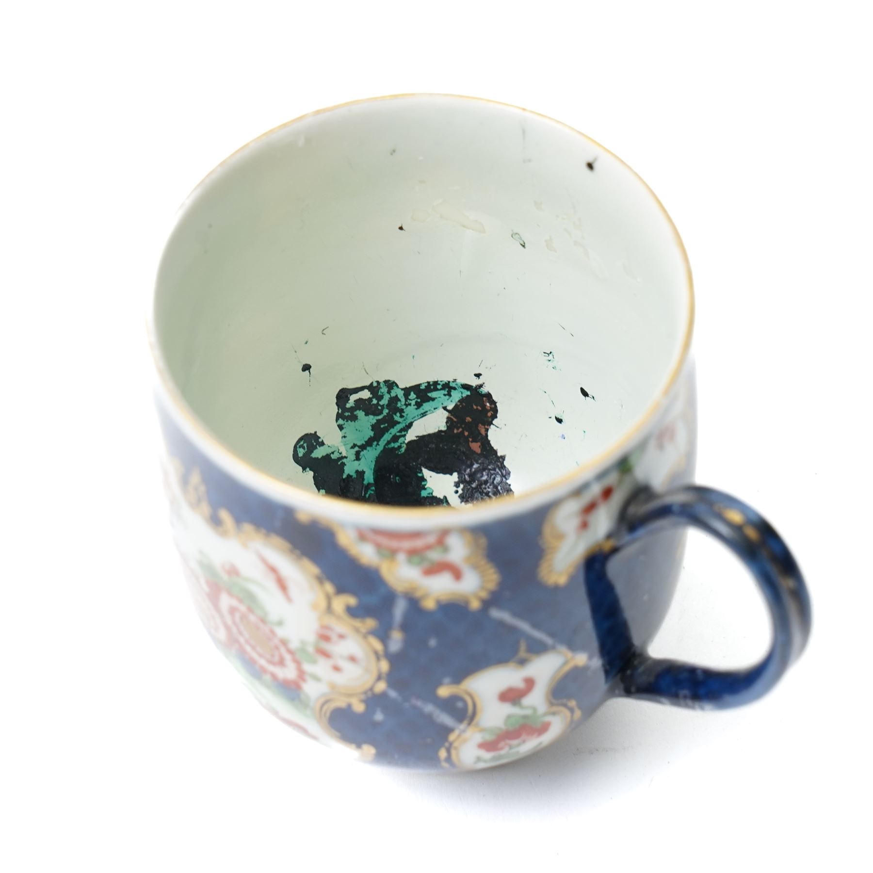 Russian, probably Gardner figure of a man pushing a wheelbarrow on gilt lined rectangular base, impressed mark, H16cm, 18th century creamware beaker with star shape decoration, 18rh century Worcester cup with panels of flowers on a blue ground and a French shell shape scent flask (4)