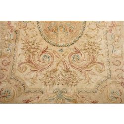 Large Aubusson design flatweave carpet, cream ground centred by oval medallion decorated with scrolling acanthus leaves and flowerheads, surrounded by floral sprays, foliate scrolls and rocaille motifs in muted pink, blue and gold tones, enclosed by conforming foliate border