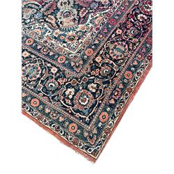 Large Persian red ground carpet, the field decorated profusely with stylised plant and trailing leaf branches, central medallion with projecting floral decoration, the spandrels decorated with further floral motifs, guarded border with repeating floral and scrolling branch pattern 