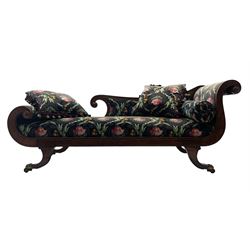 Regency period mahogany chaise longue, the moulded frame with scrolling terminals, splayed supports with cast brass hairy paw castors, upholstered in dark ground fabric with floral and foliate pattern, complimentary scatter and baluster cushions