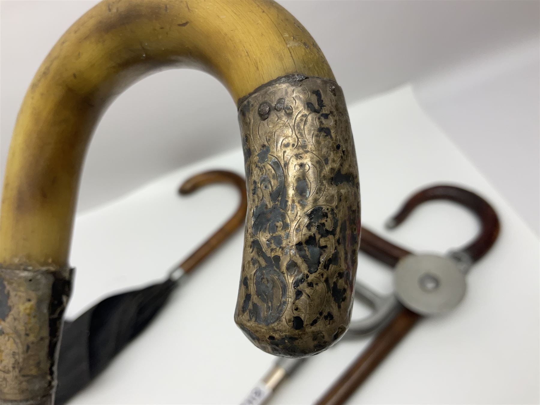 Early 20th century curved horn handle walking stick with hallmarked silver mounts, engraved L Russell 1918, together with a shooting stick by William Mills Birmingham, with leather handle, 'The Featherwaite' shooting stick and an umbrella with wooden handle