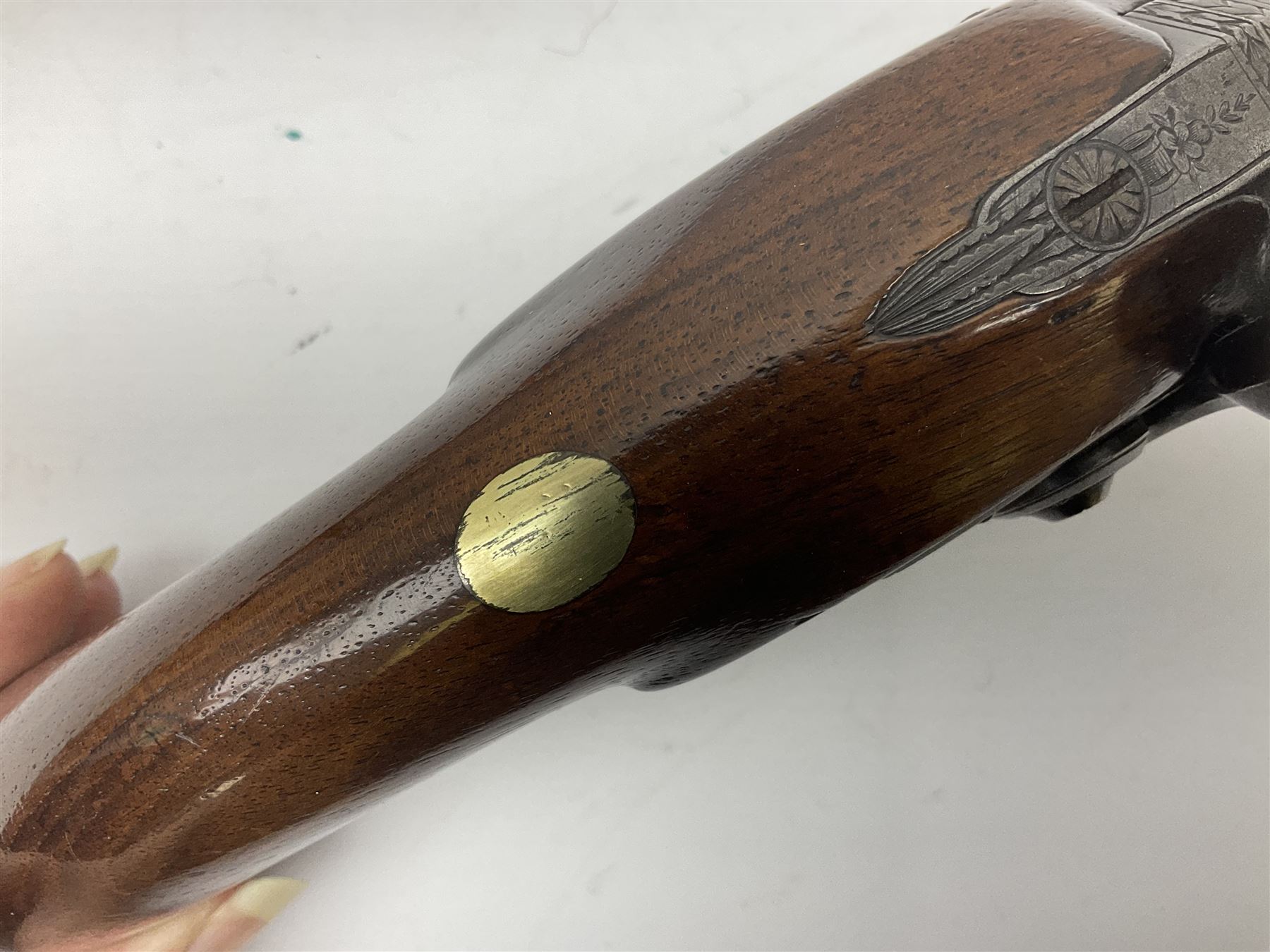 Early 19th century flintlock 16-bore overcoat/duelling pistol by William Bond Lombard Street London, the 23cm octagonal brown stub twist damascus barrel with small foresight, two barrel pins and ram rod under, inscribed Lombard Street London to the top and W. Bond to the action, full walnut stock with lightly engraved steel furniture, pineapple finial and escutcheon, half cock facility L39cm; loose mounted on later mahogany display stand with trade label