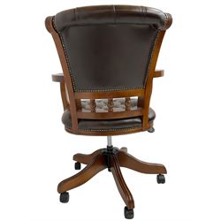 Georgian design stained beech swivel desk chair, the back carved with roundels and reeded decoration over spindle supports, upholstered in buttoned chocolate brown leather with studwork border, over a swivel and reclining action with splayed supports and castors