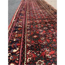 Central Asian runner rug, with repeating lozenge motif on busy red field, stylised foliate to border, 86cm x 400cm