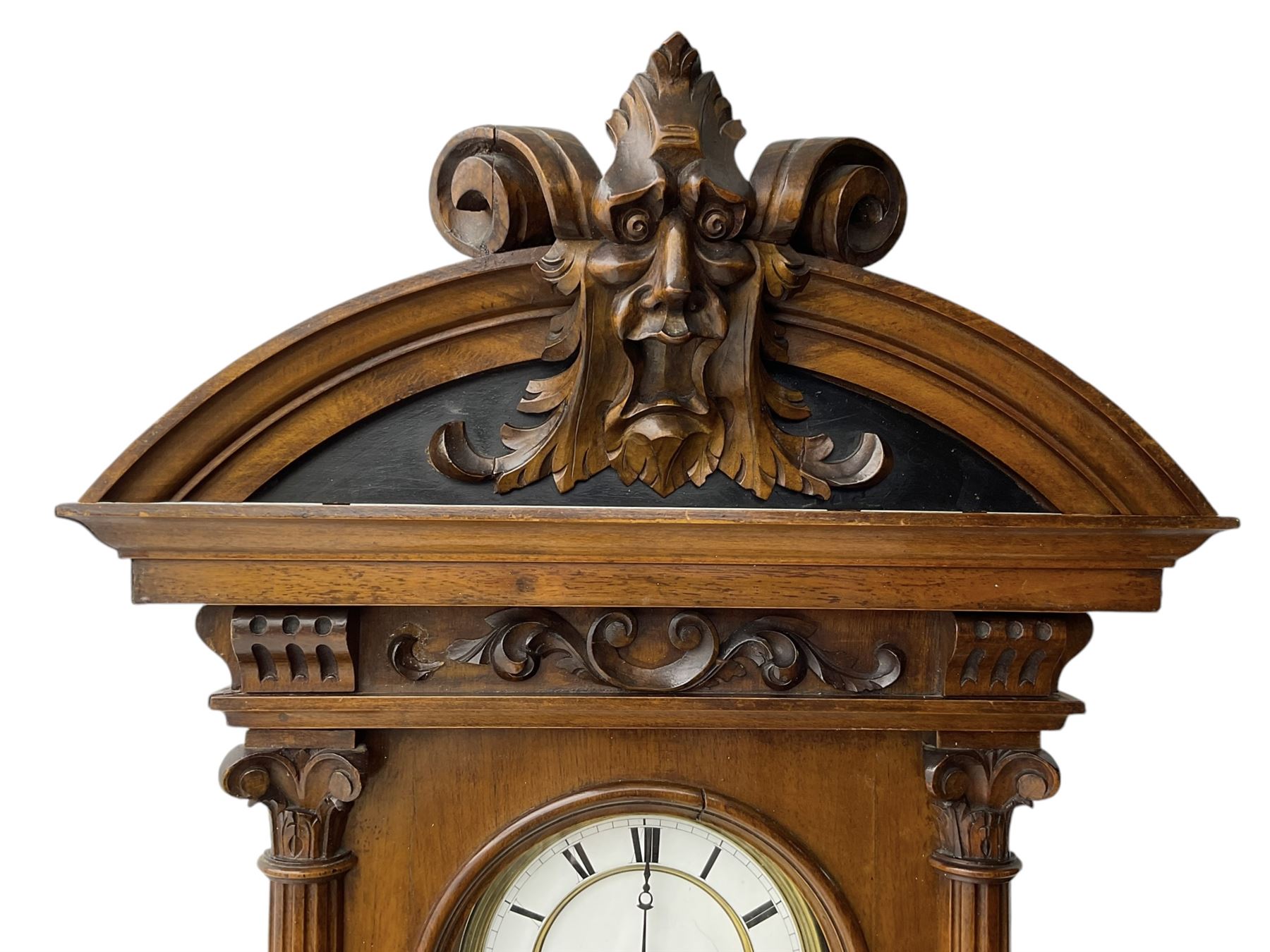 German- Late 19th century 8-day walnut cased Vienna regulator wall clock c1870,  with a broad arched pediment and heavily carved grotesque to the centre, carved frieze beneath with reeded columns to the front of the fully glazed door, carved ogee plinth and pendants to the base, two part enamel dial with Roman numerals and pierced steel hands, ebonised pendulum rod with a brass faced bob and beat plate, three matching brass cased weights and pulleys, grand sonnerie three train striking movement with a deadbeat escapement striking the quarters and hours on two coiled gongs. 
With repeat work.
