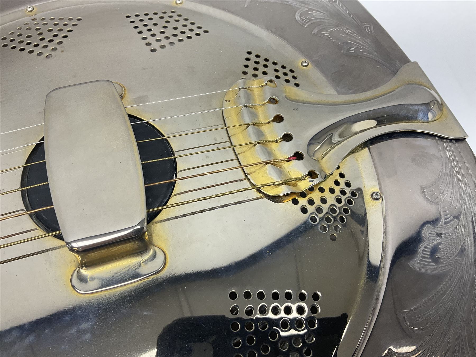 Ozark metal cased resonator guitar with all over chased foliate decoration to the polished finish and mother-of-pearl inlay to the fretboard L100cm; in Stagg hard carrying case